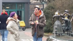Mann traegt Pappkrone und spricht mit einer Frau