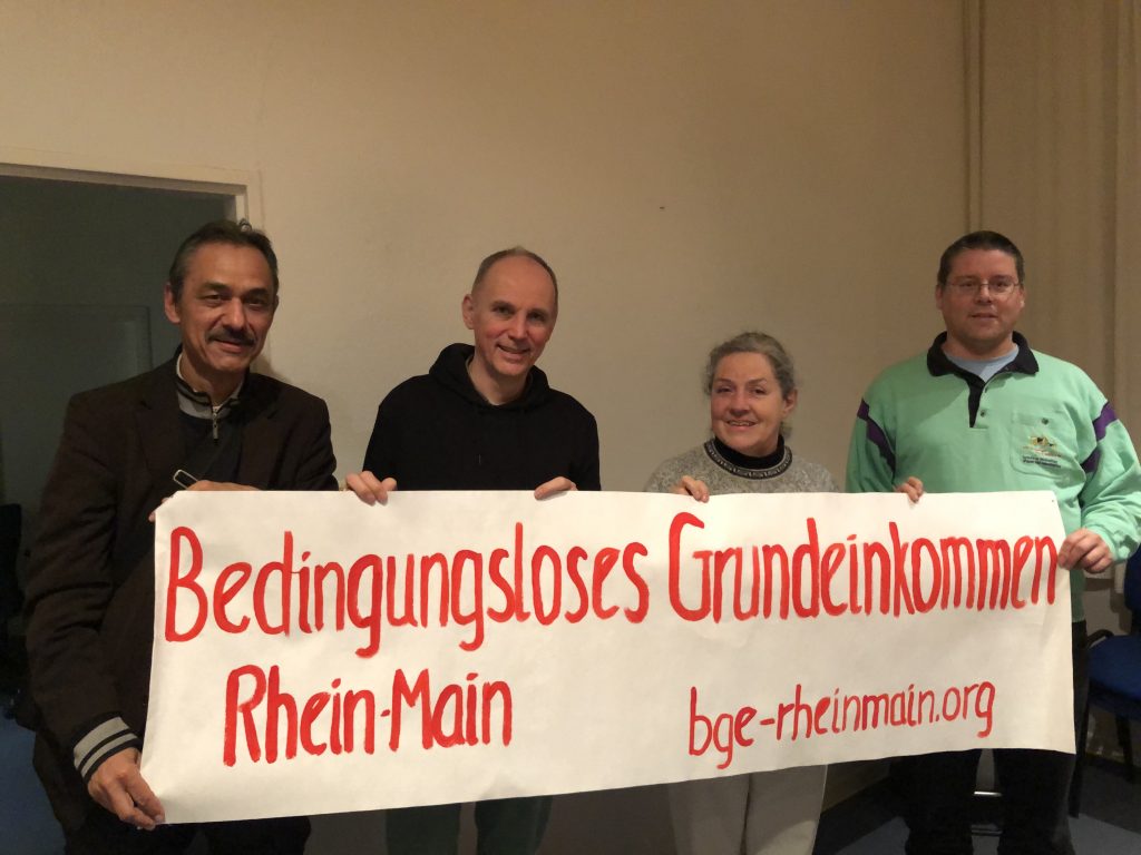 W. Strengmann-Kuhn und Aktivisten von BGE Rhein-Main halten ein Banner mit der Aufschrift: Bedingungsloses Grundeinkommen Rhein-Main